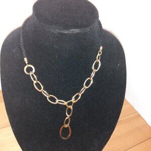 Gold tone open metal link on black corded necklace.
